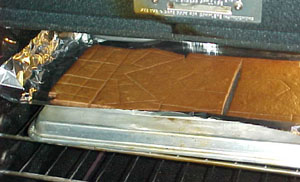 We had made a mock-up of cardboard first. Then we made a partial mock-up of gingerbread to try it out. We used the cardboard as patterns and cut out the gingebread, baked it, then cut it out again. Leaving edges helped to keep it strong and straight. Here's a picture of the baking process.
